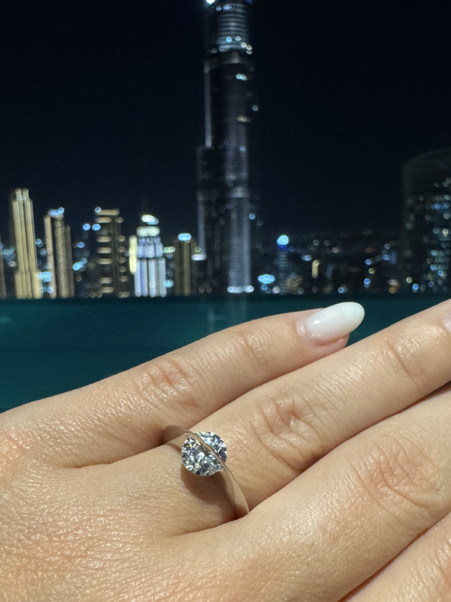 Primo piano dell’anello Giroluce indossato, con diamante che ruota, sullo sfondo lo skyline notturno di una metropoli illuminata.