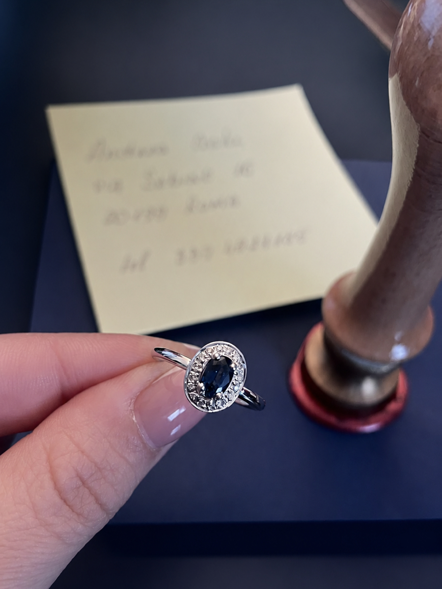 Anello Torinogioielli fotografato davanti alla busta con certificato e sigillo in ceralacca, simbolo della consegna artigianale del gioiello. Anello Torinogioielli fotografato davanti alla busta con certificato e sigillo in ceralacca, simbolo della consegna artigianale del gioiello.